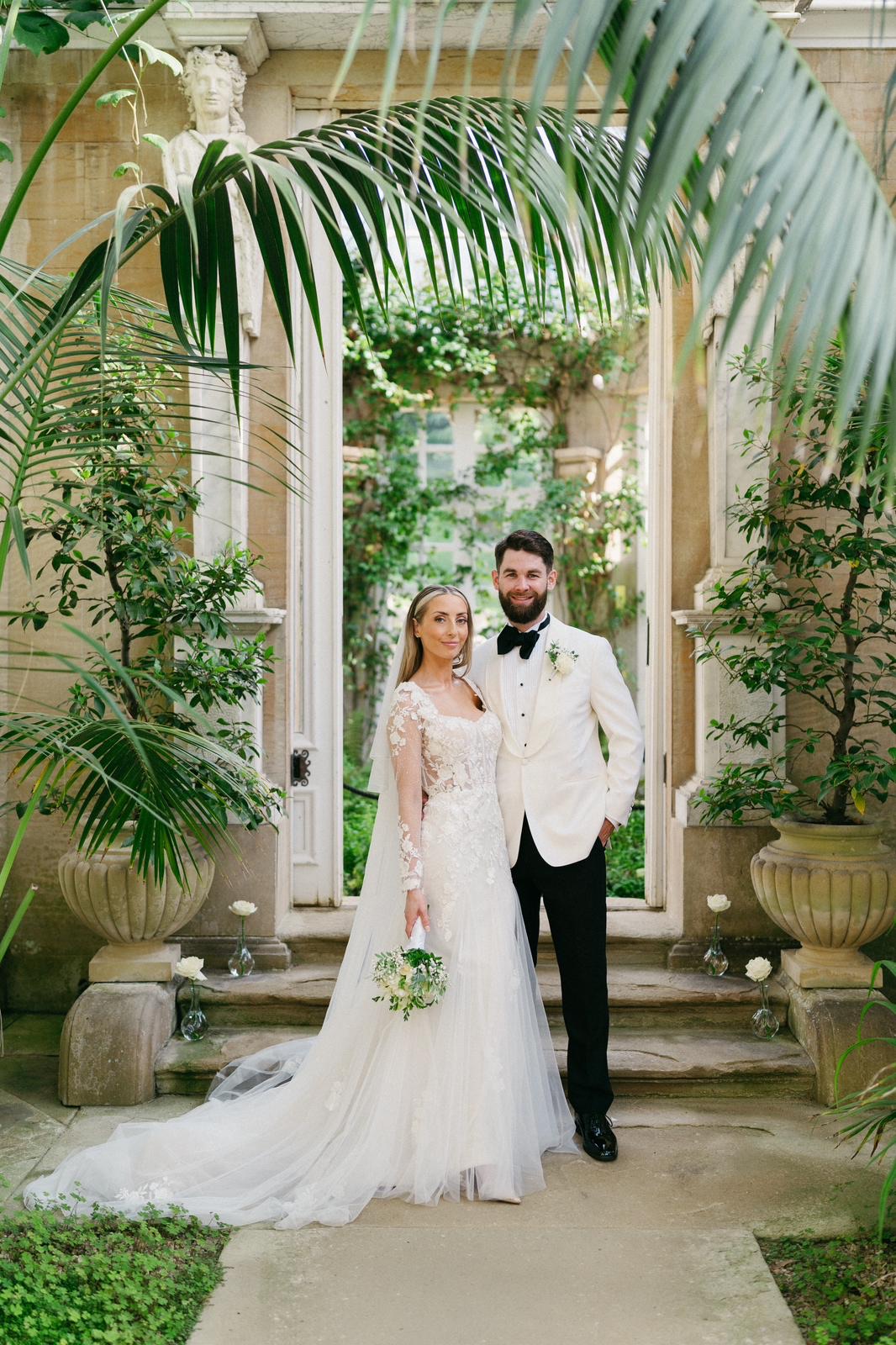Wedding couple in an ornate conservatory surrounded by greenery
