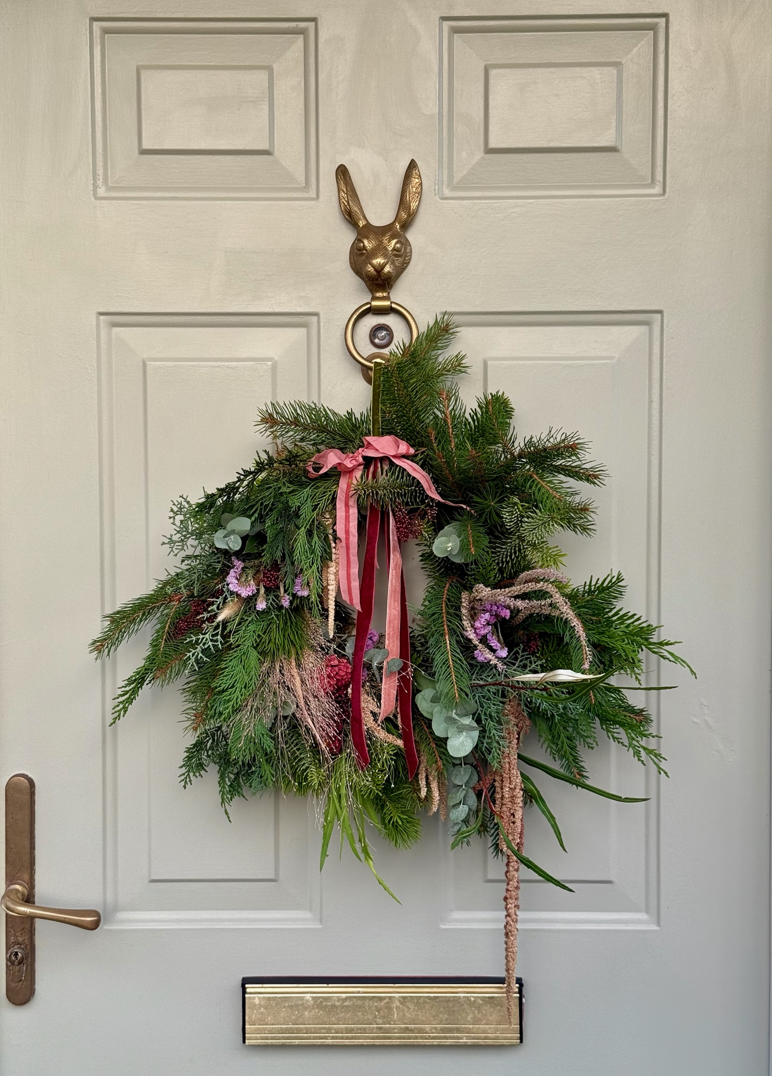 A seasonal Christmas wreath with evergreen foliage, berries and velvet ribbons