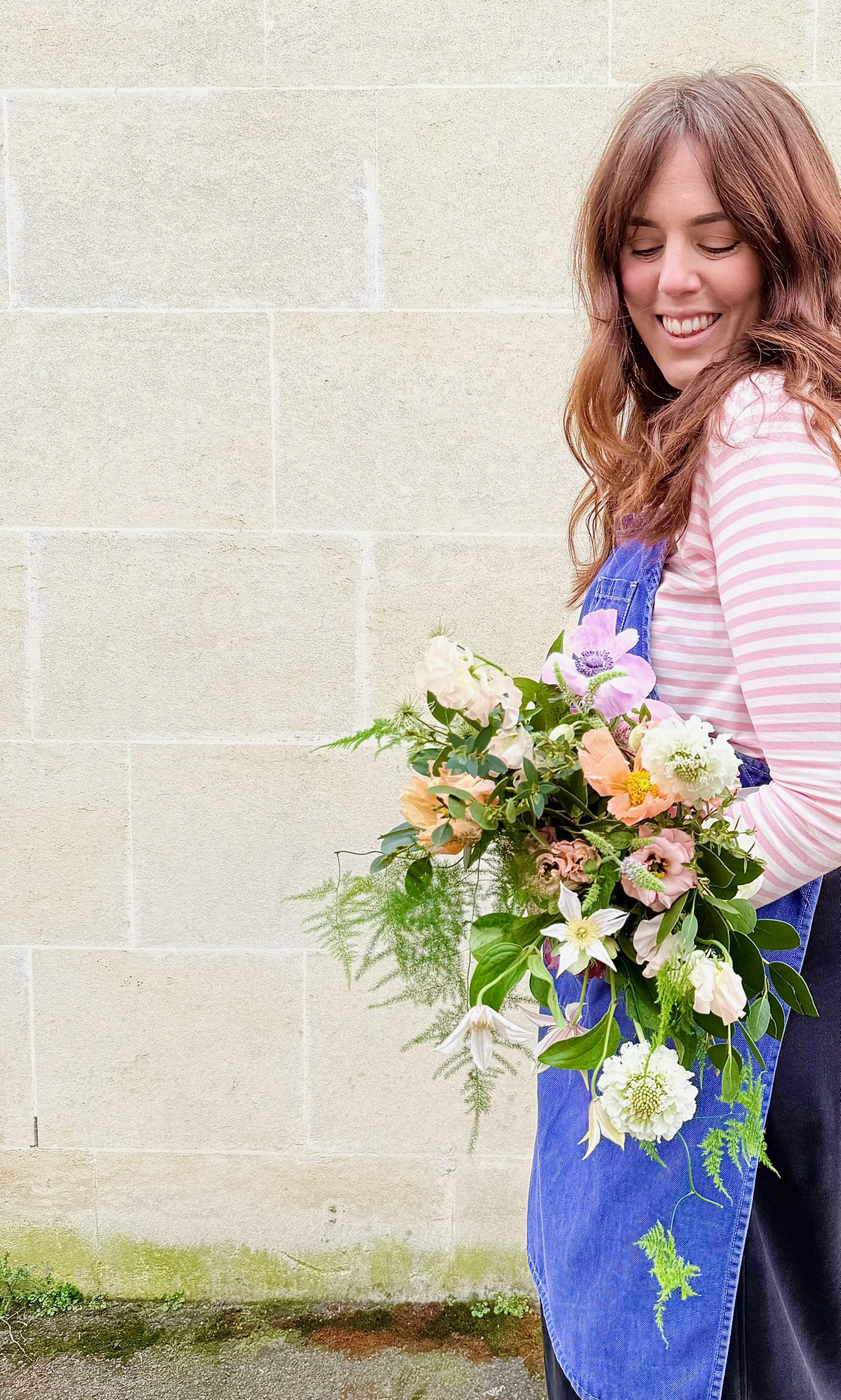 Hayley Koster holding a bouquet of seasonal flowers, smiling
