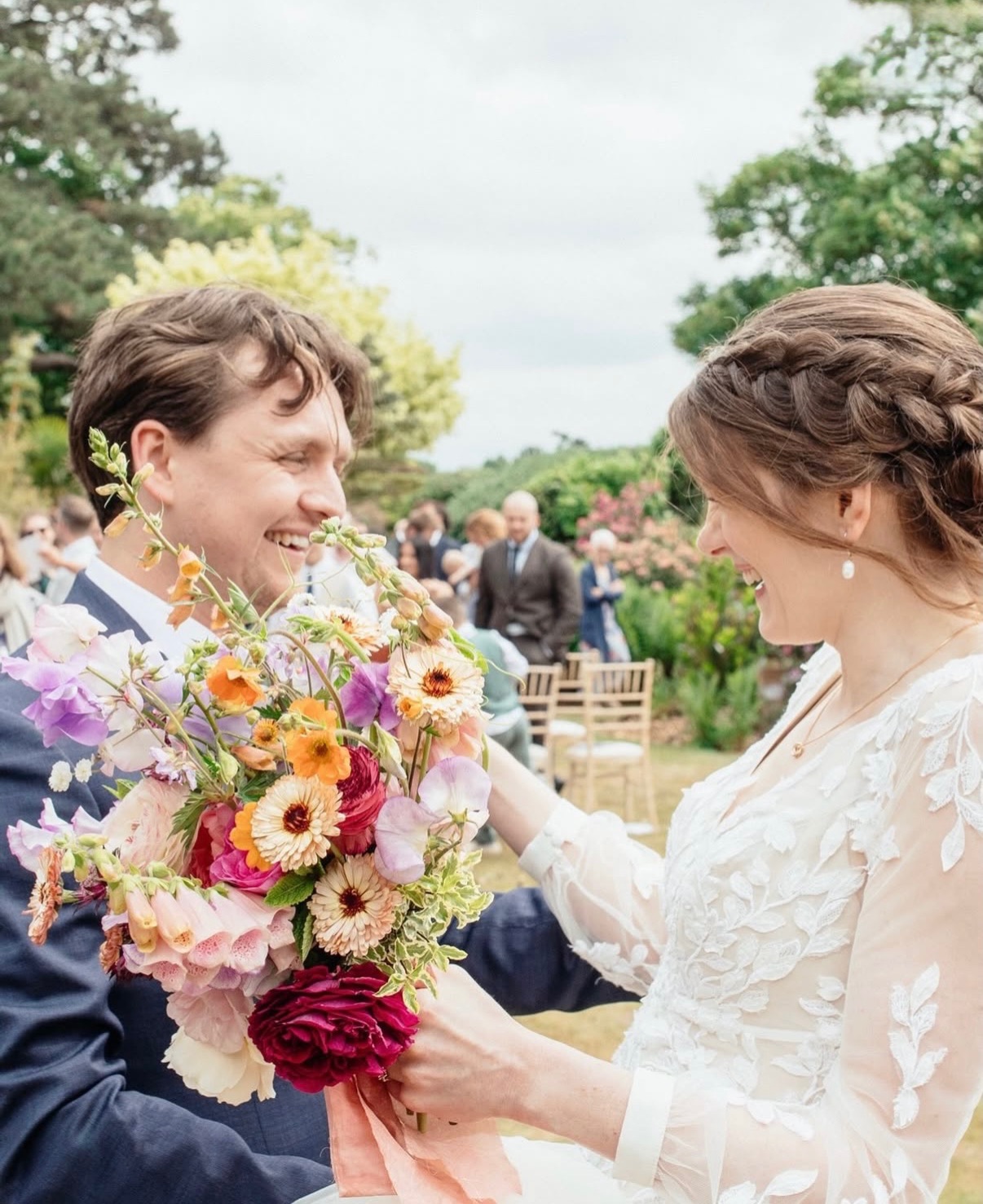 Bride and groom laughing together with a vibrant wedding bouquet