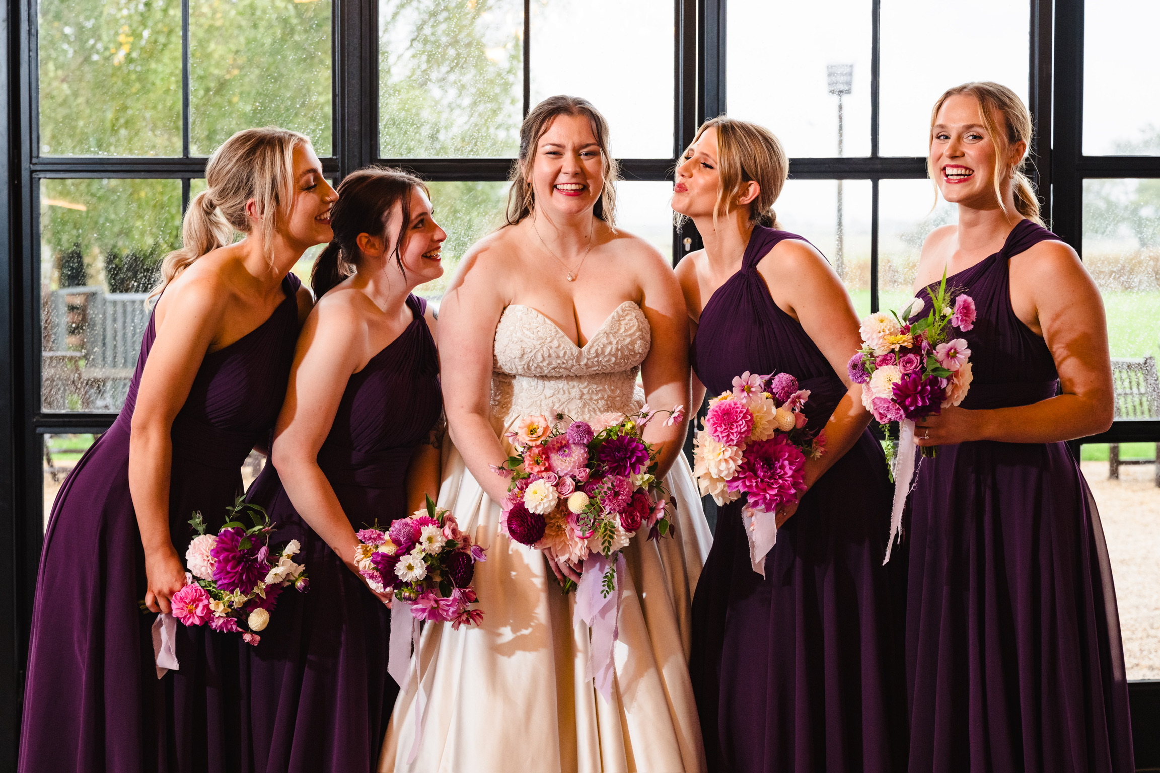 A bride and bridesmaids in purple dresses holding colourful bouquets