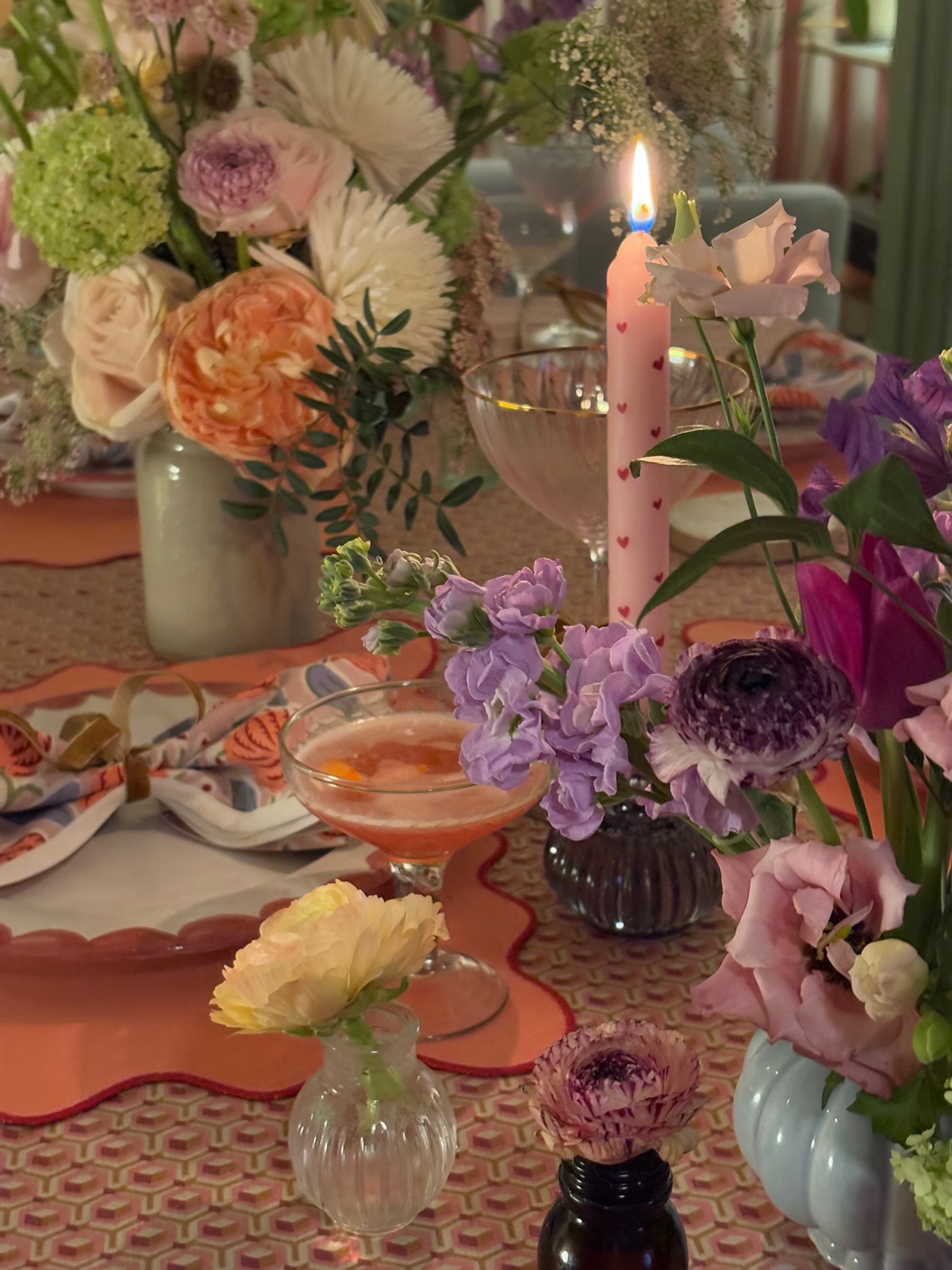 Colourful table scene with flowers, candles and cocktails